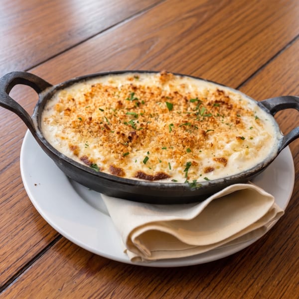 Golden baked mac and cheese in a cast iron skillet on a white plate with a napkin.